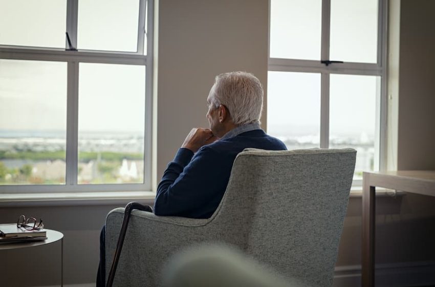 old person sat on chair looking out window