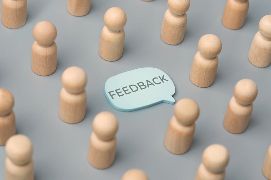 A speech bubble with the word "FEEDBACK" surrounded by human figurines.