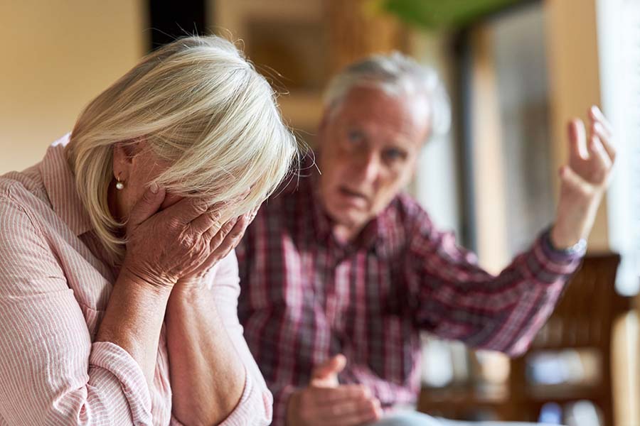 An angry looking man shouts at a woman, who has her head in her hands