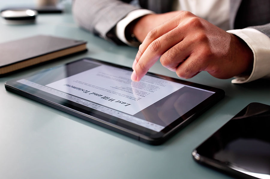 A will document is open on a tablet, with a close-up of a hand scrolling the document