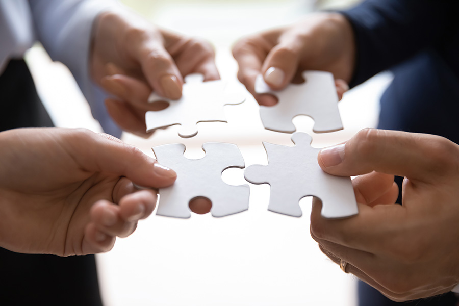 Close-up of hands holding pieces of a jigsaw together