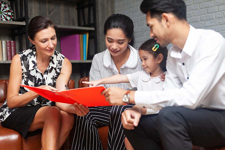 A professional woman shows a young couple and a small child some paperwork