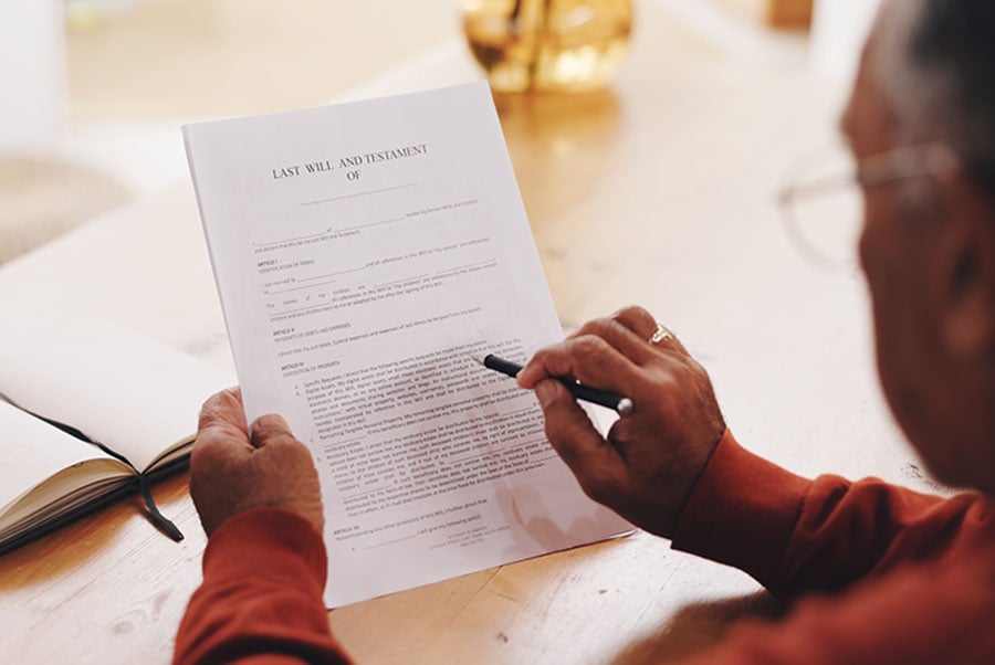 A man reads through a copy of a draft will while sitting at a table