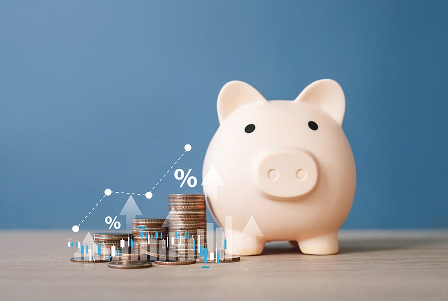 A piggy bank surrounded by piles of coins, with an overlaid graphic of a graph pointing upwards