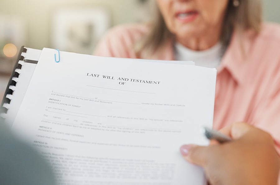 A will document is viewed in the foreground, with an older lady seen in the background