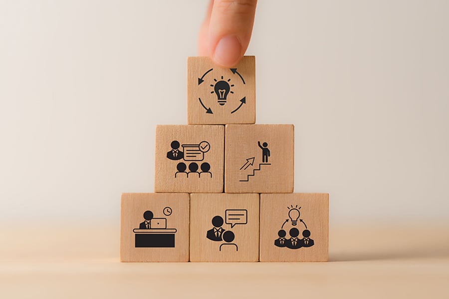 A stack of wooden bricks with simple illustrations of workplace concepts