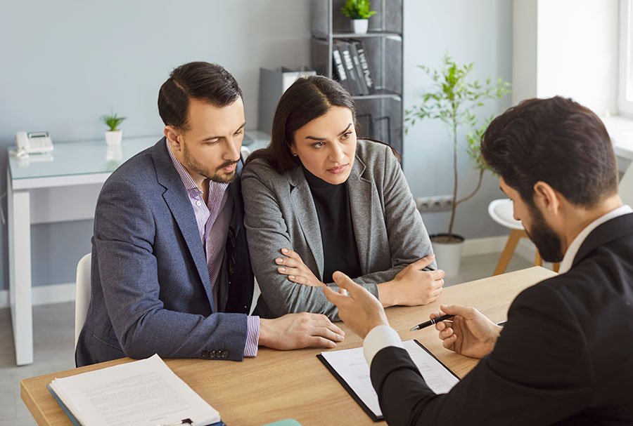 Two angry looking clients with a solicitor in an office