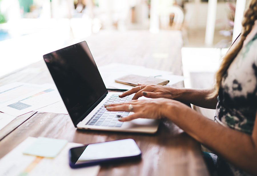 A close up of a woman's hands working on a laptop