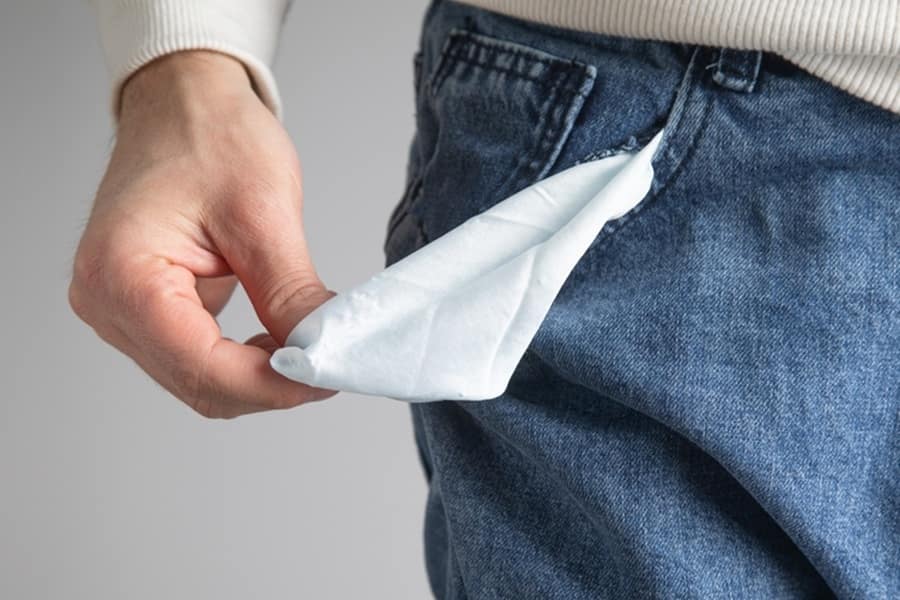 Man holds open pocket with no money in it
