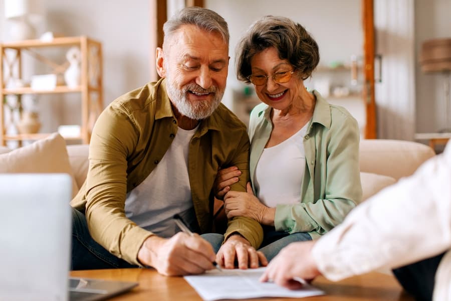 Older couple smiling and signing paper work