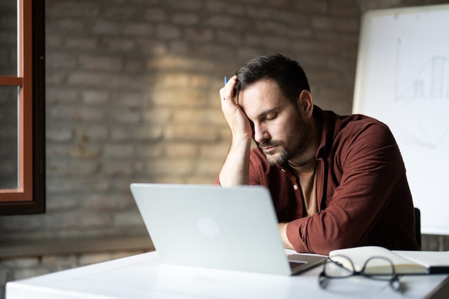 Tired businessman sitting on desk in office