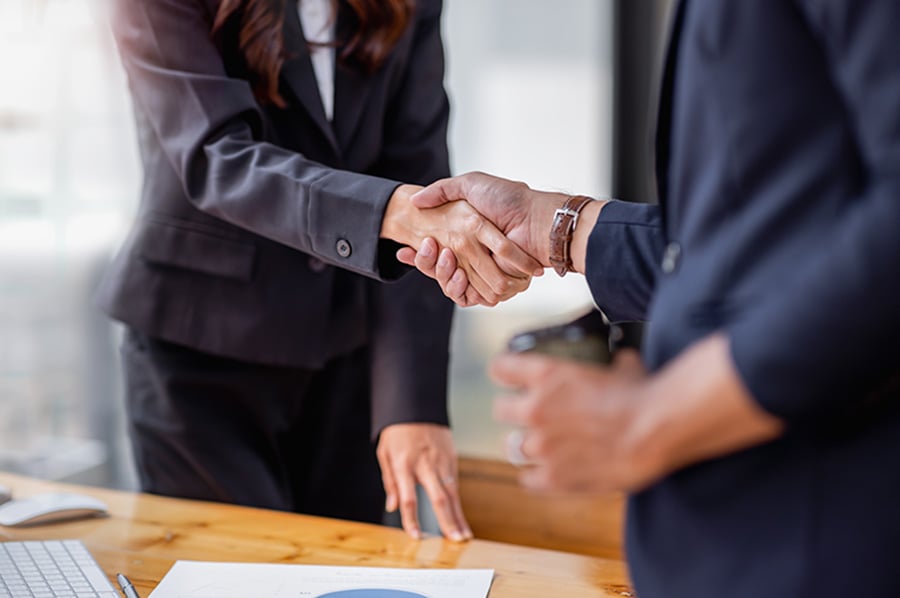 Close-up of business professionals in black suits shaking hands over a business deal
