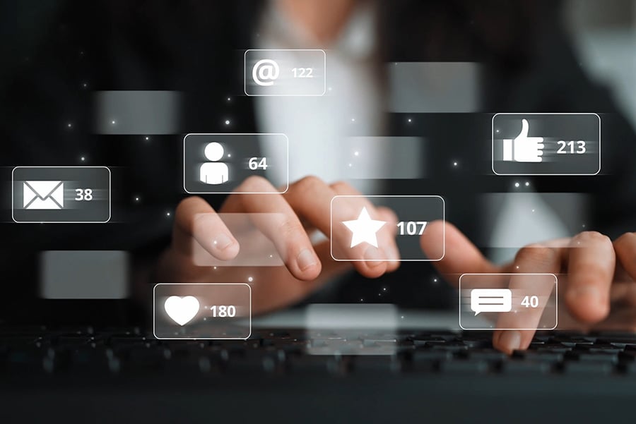 woman in a black suit and white shirt typing on a keyboard, overlaid with graphics of symbols including emails and social media icons