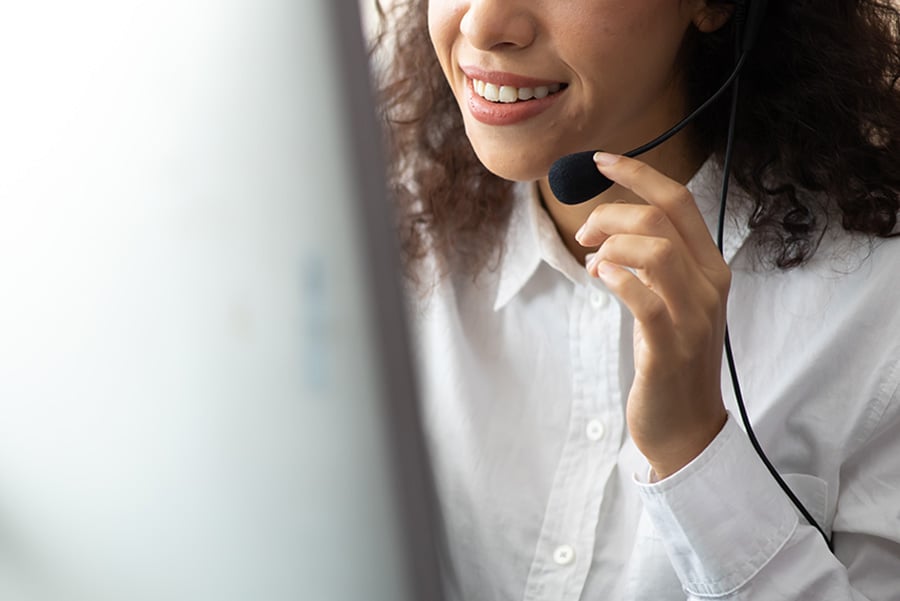 A smiling woman wearing a headset and using a computer