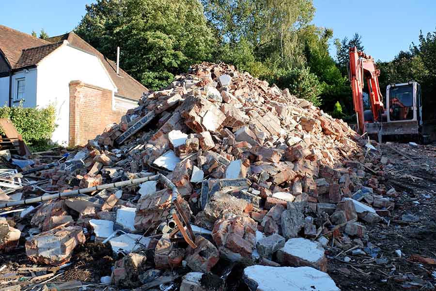 A pile of rubble after a house has been demolished by a digger