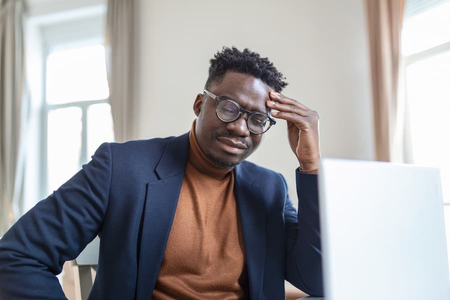 Head shot stressed young african american man touching forehead