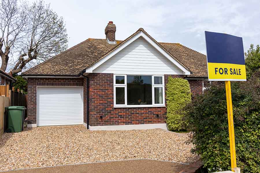 An empty bungalow with a for sale sign outside