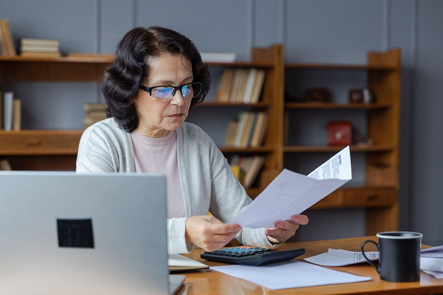 A middle-aged woman looks worried while looking at a bill