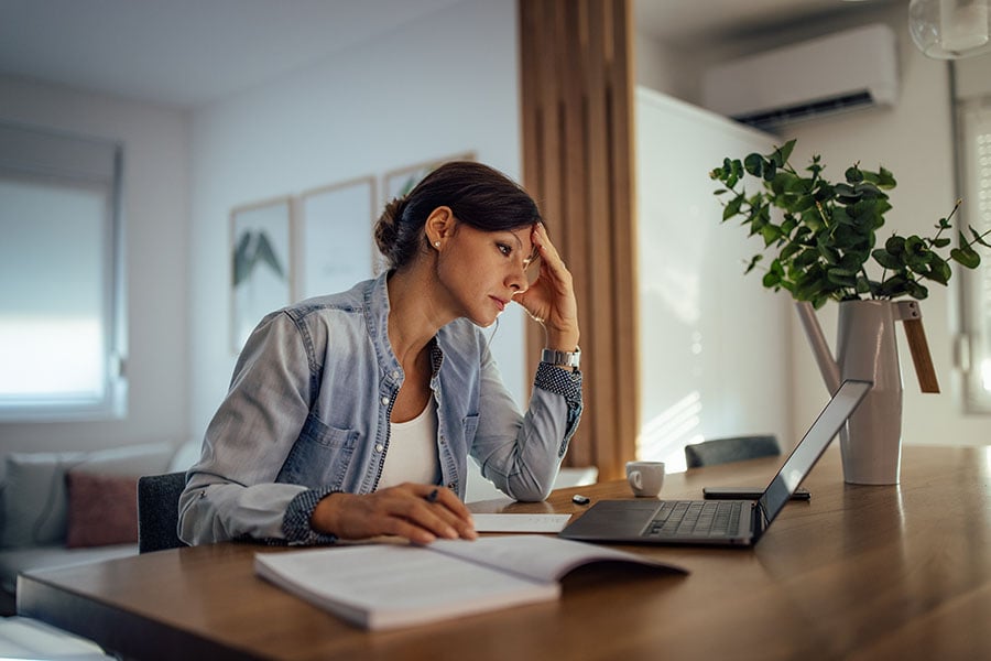 A stressed woman using AI on a laptop