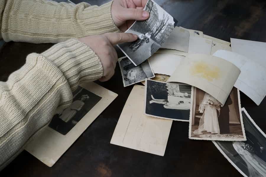 Female hands fingering old photos, vintage monochrome photographs 1950, concept of genealogy