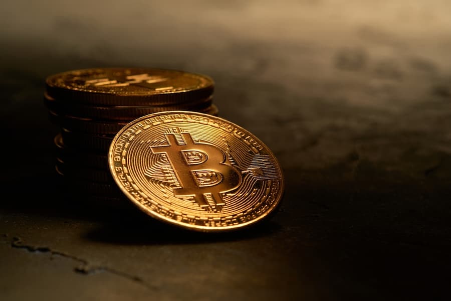 Various golden cryptocurrencies highlighting Bitcoin coin with dark textured background
