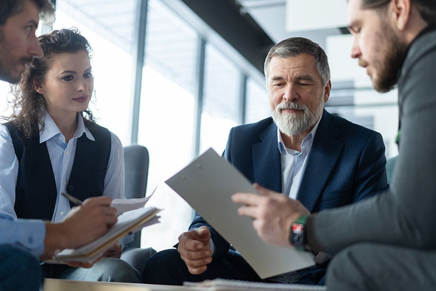 An older man and younger couple discuss documents with a lawyer