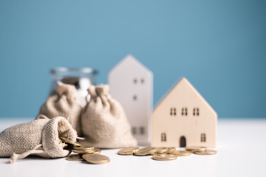 Small wooden houses surrounded by piles and bags of money