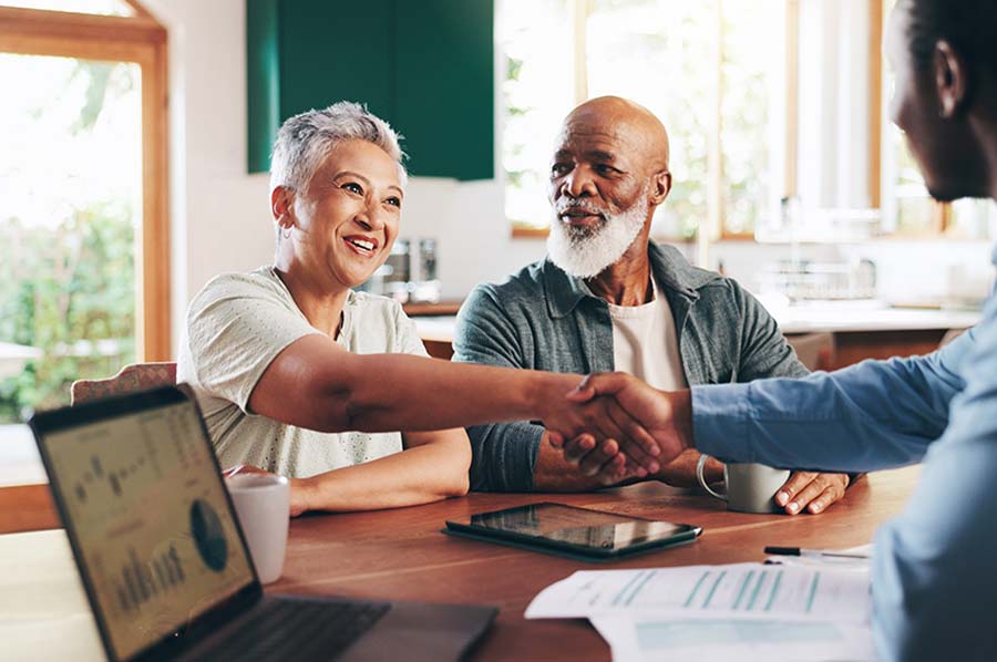 A happy older couple receiving financial advice in their kitchen
