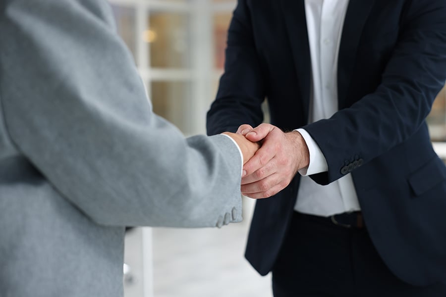 Close up of a lawyer in a black suit shaking hands with a client