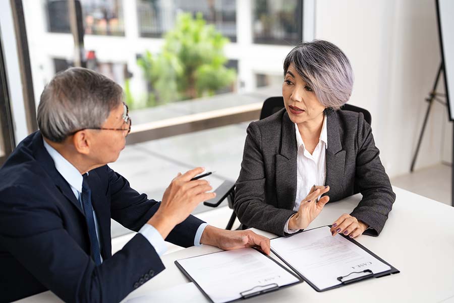 Two financial advisers in dark suits discussing paperwork
