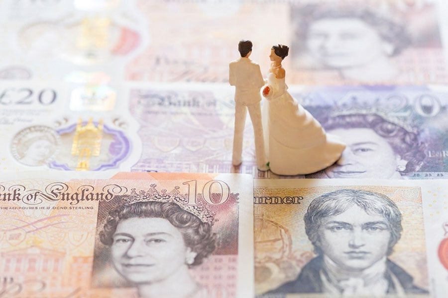 Bride and groom rigureines on top of a pile of banknotes