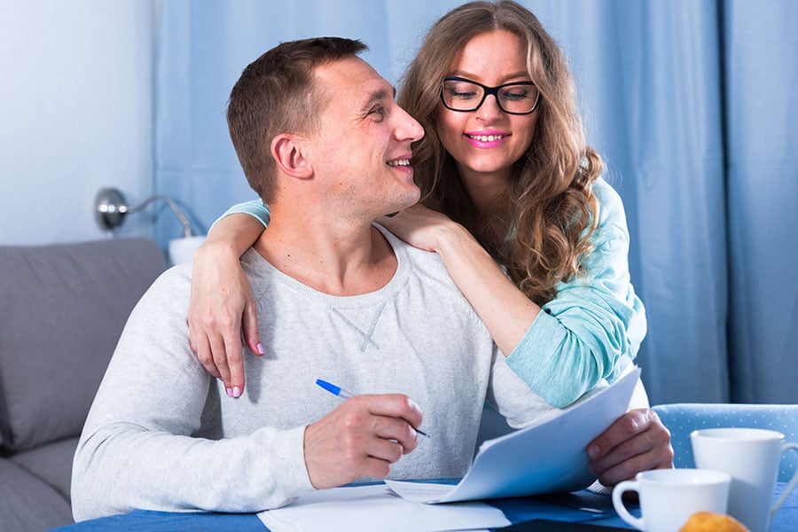 young couple filling out paperwork together, happy